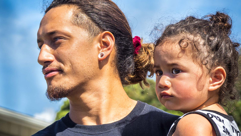 Outdoor photo of a man holding a little child